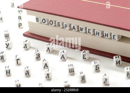 mot imagination écrit gagner lettres cyrilliques entre feuilles de livre et lettres cyrilliques dispersés sur fond blanc concept abstrait Banque D'Images