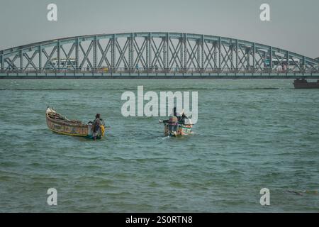 Pêcheurs sénégalais typiques avec des bateaux appelés pirogue flottant vers le célèbre pont métallique faidherbe sur le fleuve sénégal. Belle carte postale africaine.. Banque D'Images