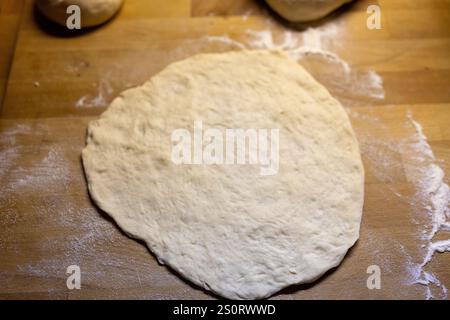 Un gros plan de pâte fraîchement roulée sur une surface en bois farinée, prête pour la cuisson. Banque D'Images