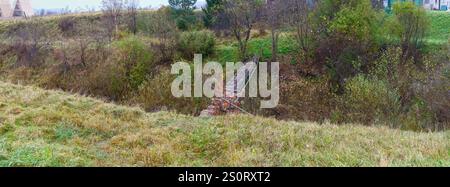 Petit pont piétonnier à travers le lit de rivière étroit et profond de la rue Shevchenko près de la rue Budivelna, Skhidnytsia, Ukraine occidentale. Banque D'Images
