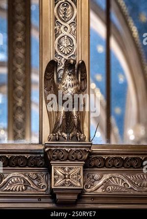 Un détail architectural orné avec une sculpture d'aigle en bronze, finement conçu avec des motifs floraux et des motifs décoratifs, placé contre un dos Banque D'Images