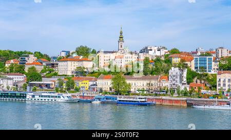La Sava traverse Belgrade, exposant les bâtiments dynamiques du front de mer et les bateaux amarrés le long du rivage sous un ciel bleu clair par une journée ensoleillée. Banque D'Images