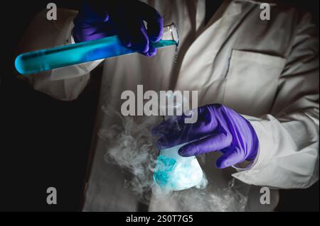 Une femme scientifique effectuant une réaction organique dans des conditions fumantes dans un laboratoire. Fumées, radioactives, fluorescence. Un arrière-plan noir d'espace de copie. Banque D'Images