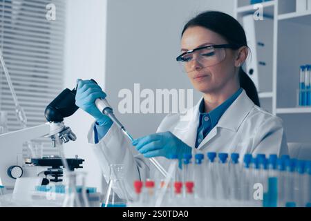 Un chercheur scientifique qualifié mène des expériences complexes dans un laboratoire moderne, en utilisant son expertise pour faire progresser les connaissances scientifiques et y contribuer Banque D'Images