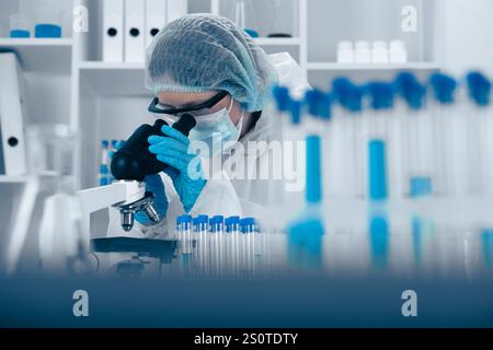 Scientifique analysant des échantillons sous microscope dans un environnement de laboratoire moderne Banque D'Images