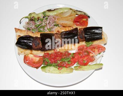 Eggplant traditionnel turc Kebab aka Patlican Kebap garni de salades servies sur assiette blanche isolée sur blanc à Adana, Turquie Banque D'Images