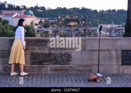 Touriste posant pour photo par plaque censée marquer l'endroit où Saint Jean de Nepomuk a été jeté dans la rivière Vltava, le 20 mars 1393. Prague. Banque D'Images