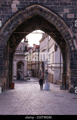 Couple de mariage retournant à leur hôtel par la Tour du pont Charles, tôt le matin. Prague, République tchèque, Tchéquie. Banque D'Images