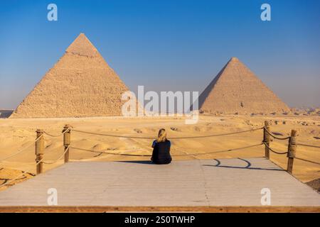 Touriste blonde assis devant les pyramides de Gizah au Caire, Egypte Banque D'Images