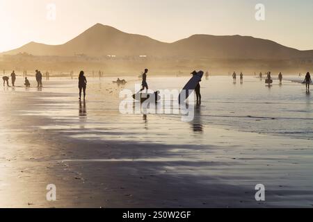 Caleta de Famara, Espagne - 30 octobre 2024 : touristes et surfeurs sur la plage de Famara, Caleta de Famara, Lanzarote, Îles Canaries, Espagne. Banque D'Images