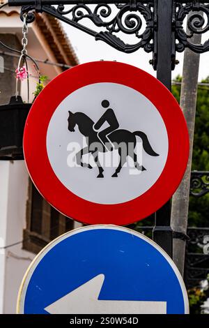 Une pancarte avec un homme qui monte à cheval dessus. Le panneau est rouge et blanc Banque D'Images