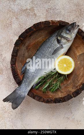 Poisson de bar frais et cru, dans une assiette en bois, vue de dessus, pas de gens. Banque D'Images