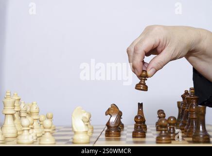 Gros plan des mains d'une femme jouant aux échecs avec un fond blanc et un espace de copie Banque D'Images