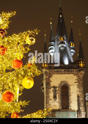 Arbre de Noël illuminé avec des ornements au premier plan, tour d'église gothique illuminé la nuit. Église notre-Dame, Prague Banque D'Images