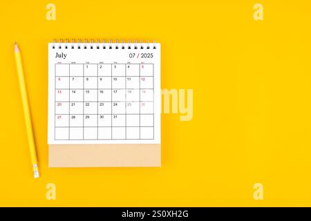 Juillet 2025 calendrier de bureau et crayon en bois sur fond de couleur jaune. Planification du temps, comptage des jours et jours fériés. Banque D'Images