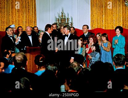 Le président des États-Unis Jimmy carter serre la main du réalisateur Mike Nichols alors que lui et la première dame Rosalynn carter, à droite, posent avec le casting de « Annie » alors qu’ils organisent un dîner en l’honneur des gouverneurs des États et de leurs conjoints dans la salle est de la Maison Blanche à Washington, DC le mardi 1er mars 1977. Crédit : Arnie Sachs/CNP Banque D'Images