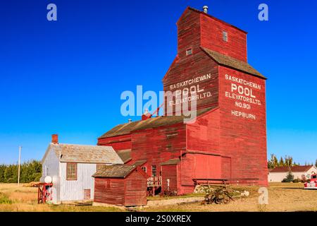 Un silo à grains rouges avec un panneau blanc qui dit Pool. Le silo est entouré d'un champ et d'une petite maison Banque D'Images