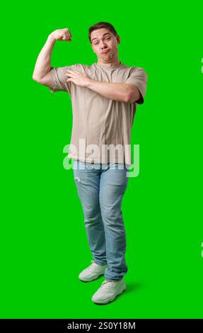 Un homme fléchit ses muscles de manière ludique sur un fond vert éclatant Banque D'Images