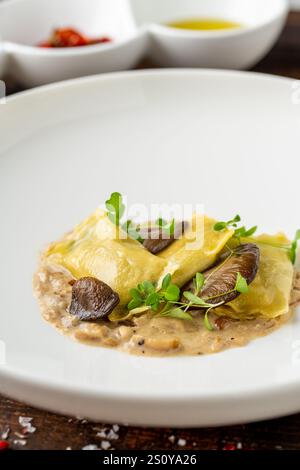 Raviolis aux champignons dans une assiette en porcelaine blanche sur une table en bois Banque D'Images