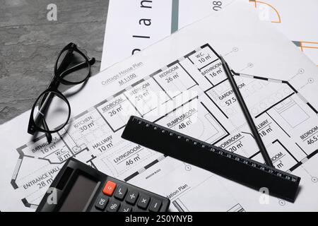 Différents dessins architecturaux, verres, calculatrice et règle sur table texturée grise, pose à plat Banque D'Images