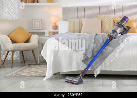 Un aspirateur sans fil reposant sur le lit à l'intérieur Banque D'Images