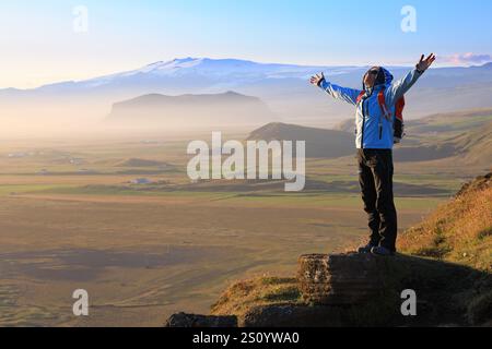 Touriste féminine appréciant la beauté du paysage fantastique de l'Islande debout au sommet d'une montagne avec les bras tendus Banque D'Images