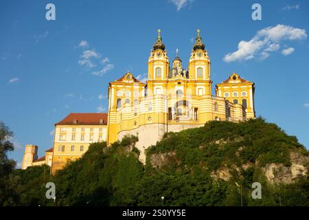 Château de l'abbaye de Melk en Autriche, immense bâtiment baroque orange sur le substrat rocheux au coucher du soleil Banque D'Images