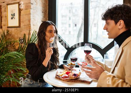 Un couple heureux profite d'un repas romantique avec du vin, célébrant leur amour dans un endroit confortable. Banque D'Images