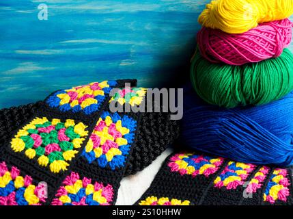 Carré de grand-mère en coton coloré sur fond d'écheveaux multicolores dans un panier en osier. Texture crochet gros plan photo. Tricoté zigzag Banque D'Images
