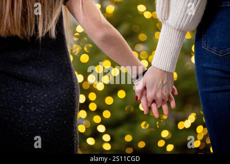 Un moment chaleureux et intime partagé entre deux personnes se tenant doucement la main au milieu des belles lumières festives Banque D'Images