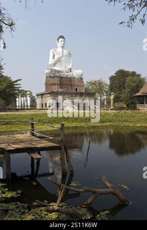 Une très grande statue de Bouddha se dresse près d'un étang à Wat Ek Phnom, un temple atmosphérique, partiellement ruiné du XIe siècle, à 11 km au nord de Battambang, au Cambodge. Banque D'Images