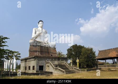 Une très grande statue de Bouddha se dresse près d'un étang à Wat Ek Phnom, un temple atmosphérique, partiellement ruiné du XIe siècle, à 11 km au nord de Battambang, au Cambodge. Banque D'Images