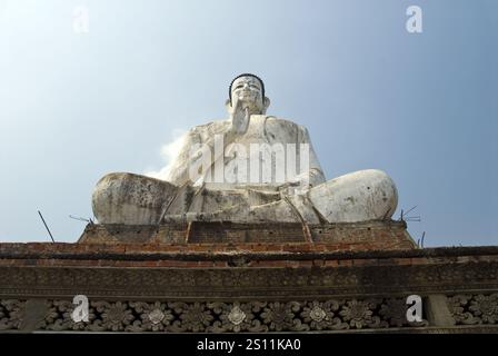 Une très grande statue de Bouddha se dresse près d'un étang à Wat Ek Phnom, un temple atmosphérique, partiellement ruiné du XIe siècle, à 11 km au nord de Battambang, au Cambodge. Banque D'Images