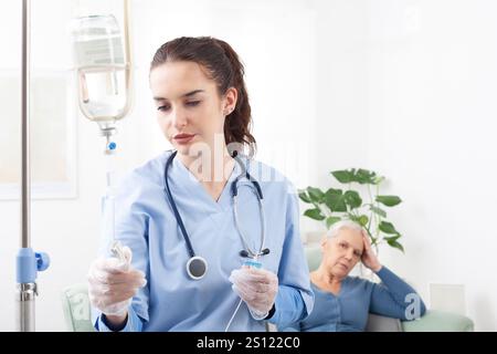 La jeune infirmière amicale ou le médecin aide la femme âgée malade patient dans la réception de perfusion goutte à goutte IV et la thérapie d'injection de vitamine assis sur le canapé dans M. Banque D'Images