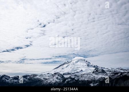 Les taches bleues du ciel indiquent un modèle de dégagement dans les nuages qui ont récemment laissé tomber de la neige fraîche sur le sommet du mont Baker - montré dans le tiers inférieur de l'image Banque D'Images