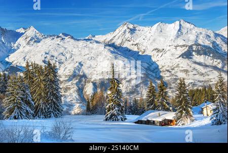 paysage d'hiver en montagne couverte de neige sous ciel bleu et chalet au pied des montagnes dans une station de ski en tarentaise - france Banque D'Images