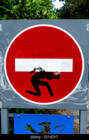 Little Man collé à un panneau « interdiction d’entrée » porte la lourde barre transversale, France, Bretagne, Pont-Croix Banque D'Images