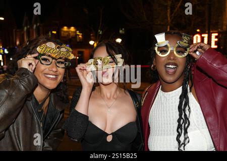 Broad Street, Birmingham 31 décembre 2024 - trois femmes posent pour une photo avec des lunettes NYE 2025 mais doivent s'accrocher à eux en raison du vent fort. - Les fêtards sont partis dans le centre-ville de Birmingham tôt la Saint-Sylvestre. Crédit : British News and Media/Alamy Live News Banque D'Images