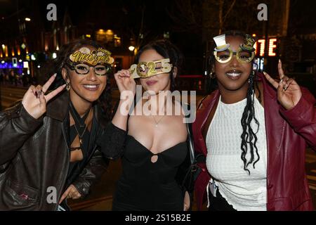 Broad Street, Birmingham 31 décembre 2024 - trois femmes posent pour une photo avec des lunettes NYE 2025 mais doivent s'accrocher à eux en raison du vent fort. - Les fêtards sont partis dans le centre-ville de Birmingham tôt la Saint-Sylvestre. Crédit : British News and Media/Alamy Live News Banque D'Images