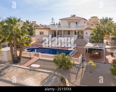 Villa de style méditerranéen offrant une grande piscine, plusieurs terrasses, un coin repas extérieur et une végétation luxuriante pour se détendre et se divertir. Banque D'Images