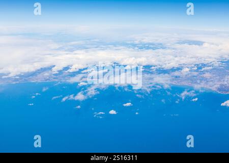 Vue aérienne de l'océan et des nuages moelleux, mettant en valeur la vaste étendue bleue depuis une fenêtre d'avion. Perspective aérienne de la mer et des nuages, capturée Banque D'Images