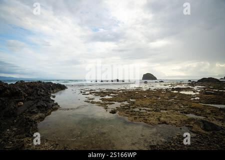 Superbe plage de Diguisit à Baler, Philippines. Il dispose d'une côte accidentée bordée de formations rocheuses et d'un paysage marin serein. La showca au premier plan Banque D'Images