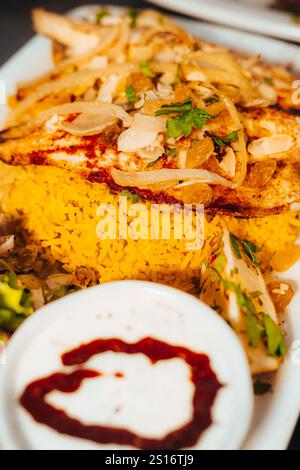 Gros plan de poisson grillé sur riz safran avec oignons et garnitures d'amandes Banque D'Images