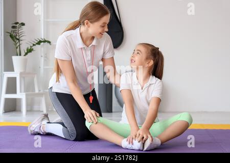 Mignonne petite fille de formation avec entraîneur dans le gymnase Banque D'Images