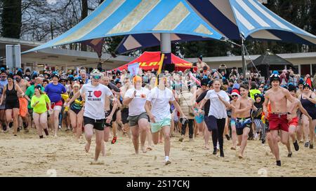 Haltern, Allemagne. 1er janvier 2025. Les nageurs courent vers l'eau. Les participants, dont beaucoup en costumes, s'amusent à la baignade annuelle du jour de l'an au lac Haltern près de la ville de Haltern am See. Près de 700 participants inscrits, un record pour l'événement, courent à travers la plage de sable naturel du lido du lac et dans l'eau glacée pour prendre un bain et nager pour la charité (cette année, une soupe populaire pour ceux dans le besoin). Plusieurs centaines d'autres sont venus soutenir et regarder les nageurs qui se réchauffent avec du thé, du vin chaud et de la nourriture copieux sur la plage par la suite. Crédit : Imageplotter/Alamy Live News Banque D'Images