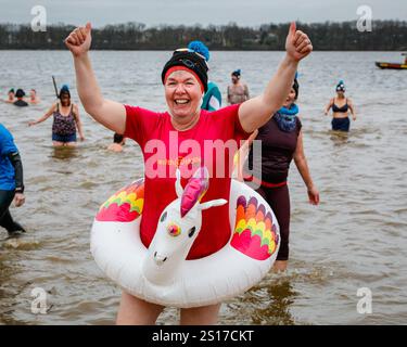 Haltern, Allemagne, 1er janvier 2025. Un nageur est heureux d'avoir bravé l'eau froide. Les participants, dont beaucoup en costumes, s'amusent à la baignade annuelle du jour de l'an au lac Haltern près de la ville de Haltern am See. Près de 700 participants inscrits, un record pour l'événement, courent à travers la plage de sable naturel du lido du lac et dans l'eau glacée pour prendre un bain et nager pour la charité (cette année, une soupe populaire pour ceux dans le besoin). Plusieurs centaines d'autres sont venus soutenir et regarder les nageurs qui se réchauffent avec du thé, du vin chaud et de la nourriture copieux sur la plage par la suite. Banque D'Images