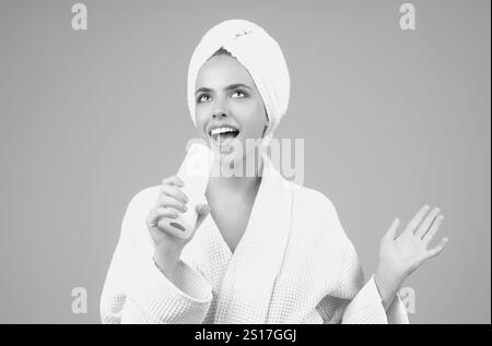 Portrait de la jeune femme tient bouteille shampooing et revitalisant. Produit de beauté, bouteille de baume. Jeune femme avec produit de soins capillaires. Fille appliquant les cheveux condi Banque D'Images