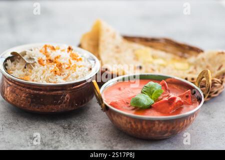Poulet tikka masala nourriture épicée à la viande de curry beurre poulet avec riz et pain naan sur fond foncé gros plan. Poulet tikka masala avec riz et pourriture Banque D'Images