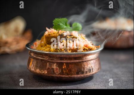 Biryani pulao indien fumé épicé dans un bol doré avec plat de riz basmati indien avec curry de viande de poulet Ramadan Kareem, Eid. Bol de service en laiton avec Whit Banque D'Images