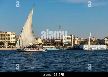 Assouan, Egypte ; 18 janvier 2024 : Voir felouques et croiseurs fluviaux sur le Nil dans un contraste de rivière à Assouan. Cette scène montre des felouques traditionnels. Banque D'Images